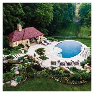 Overhead view of a swimming pool and a gazebo. It appears to be located down a hill, with greenery incorporated all around.
