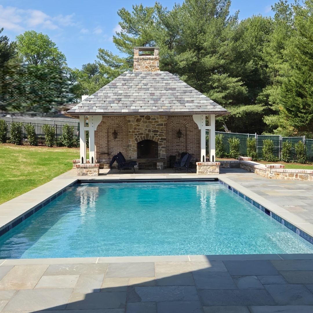 Rectangular gunite pool facing stone pavilion with fireplace