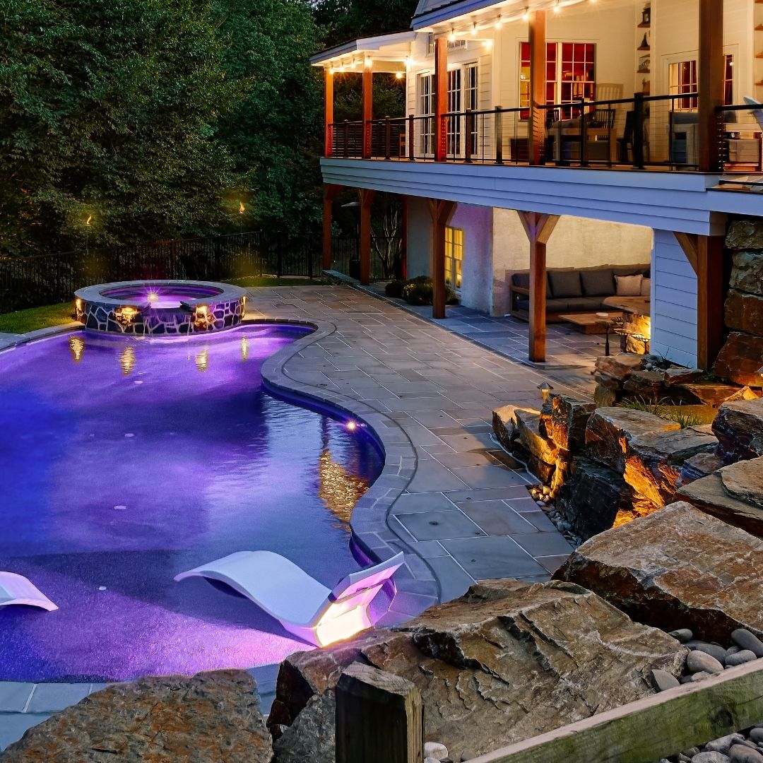 Pool illuminated with purple LED lights and glowing loungers.