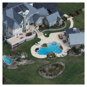 An overhead view of an expansive estate with two custom swimming pools seamlessly integrated into the terrain.
